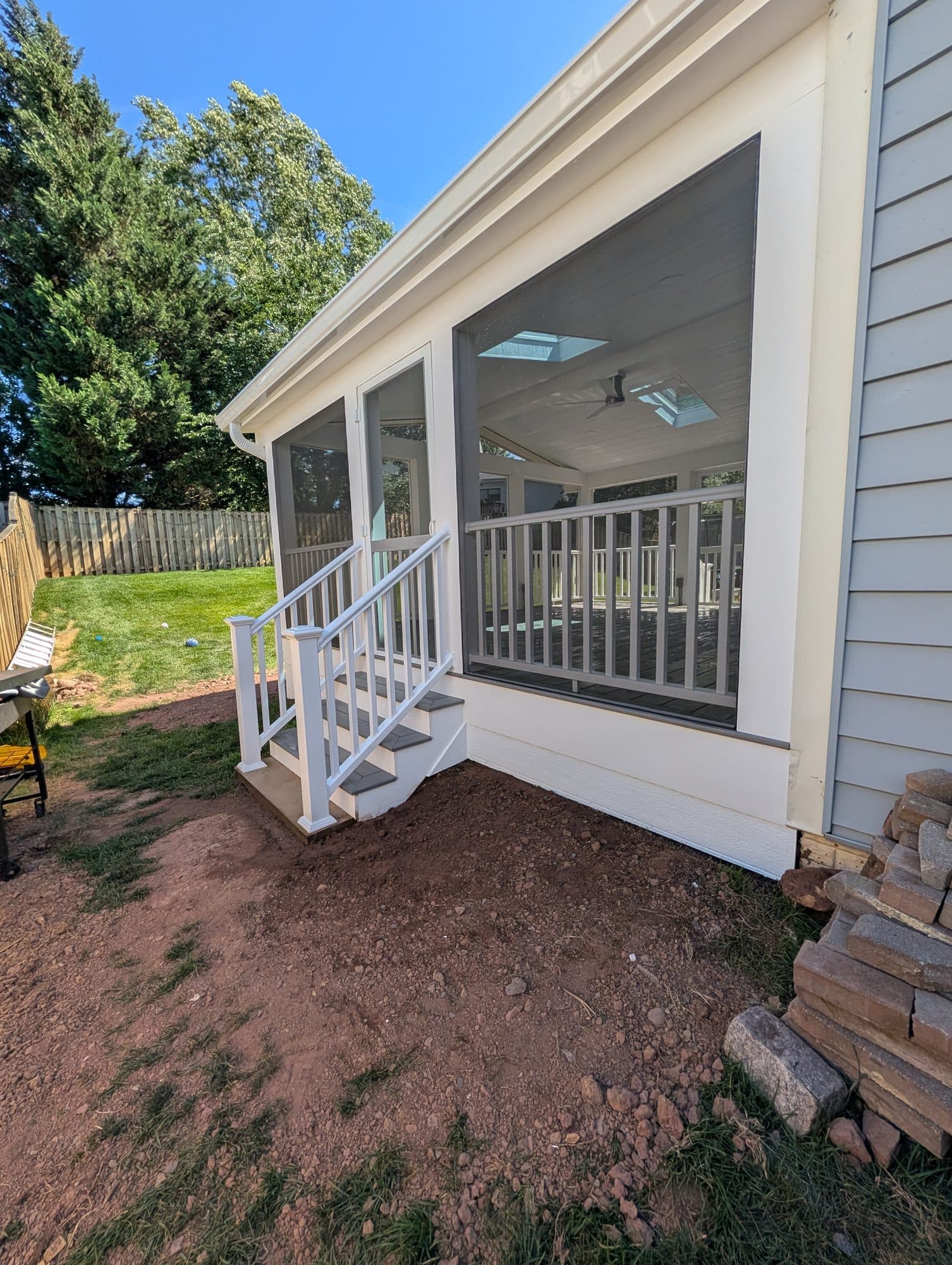 Screened-in porch exterior with stairs, railing, and skylights