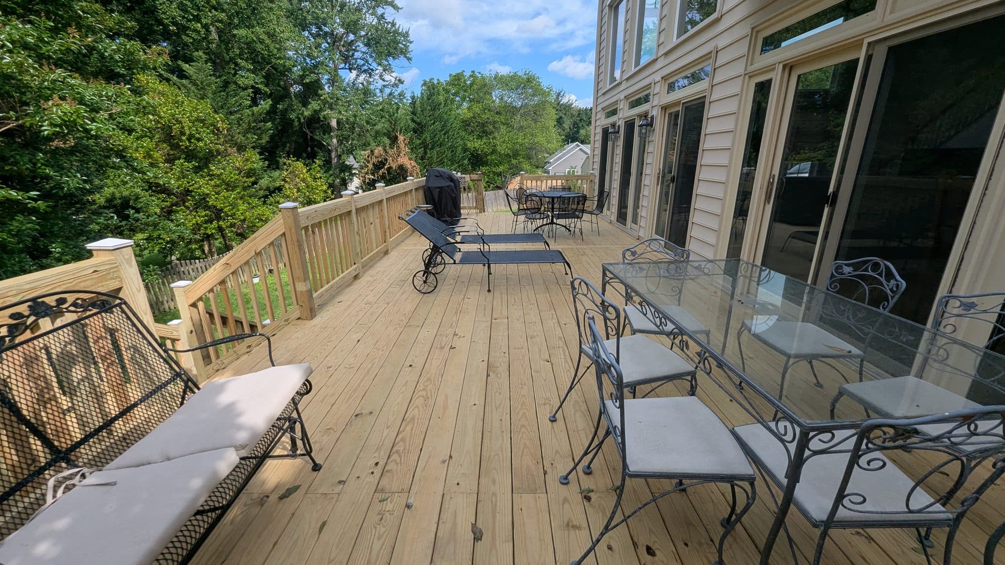 Large open wood deck furnished with a dining table and lounge chairs